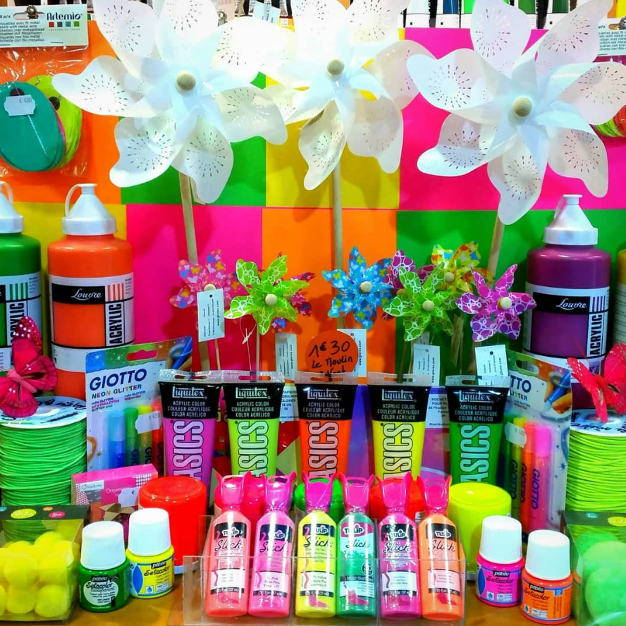 Présentation de matériel artistique coloré, comprenant de la peinture, des stylos et des moulins à vent décoratifs.