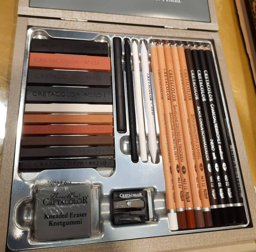 Un coffret de dessin avec fusain et crayons, comprenant une gomme mie de pain et un taille-crayon.