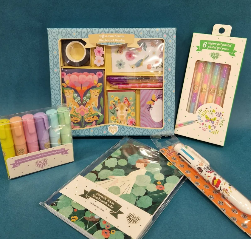 Coffret de papeterie comprenant des stylos colorés, un bloc-notes et des cadeaux dans un emballage floral.