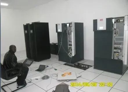 A man is working on a laptop in a room with servers