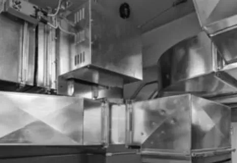 A black and white photo of a kitchen with stainless steel ducts.