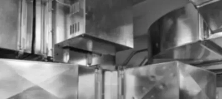A black and white photo of a kitchen with stainless steel ducts.