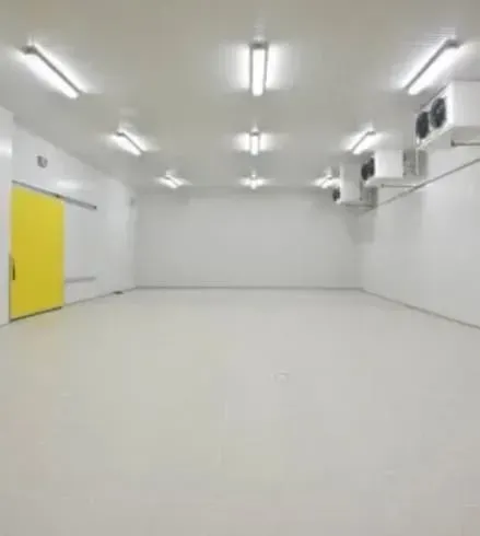 A large empty room with white walls and a yellow door.