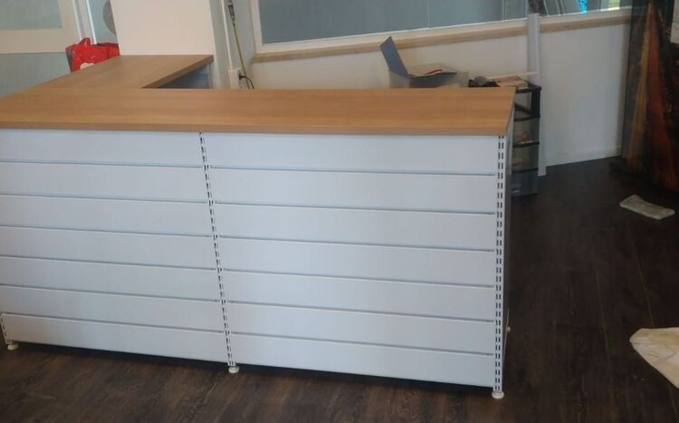 En una habitación hay un mostrador blanco con tapa de madera.