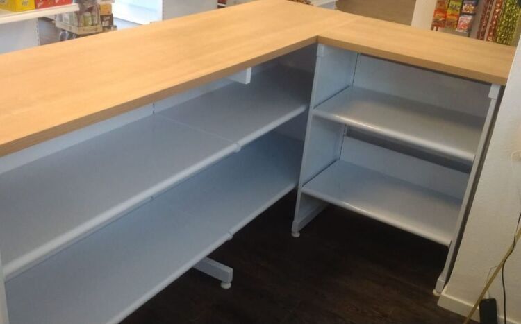 Un mostrador con estantes y una tapa de madera en una tienda.