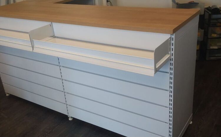 Un mostrador blanco con tapa de madera y cajones.