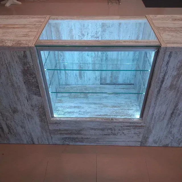Un mostrador de madera con vitrina de cristal y estantes.