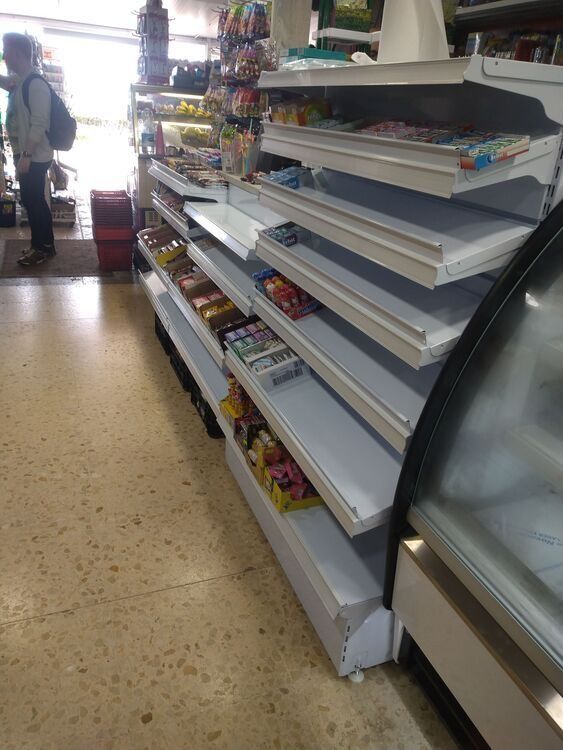Un hombre está de pie en una tienda con estantes vacíos.