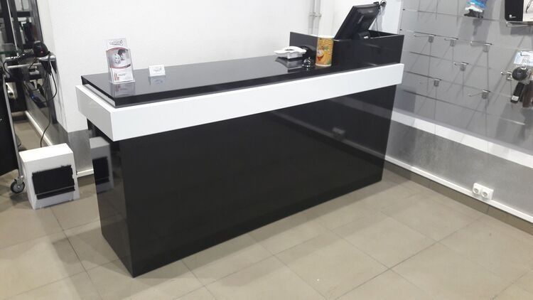 Un mostrador en blanco y negro en una habitación con una computadora encima.