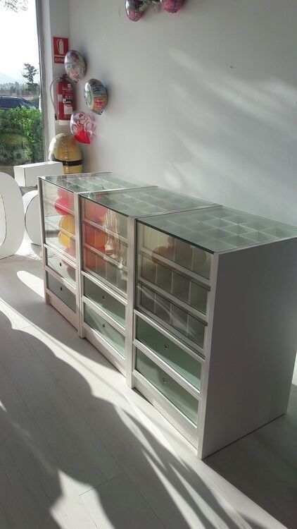 Una fila de gabinetes blancos con puertas de vidrio en una habitación con globos en la pared.