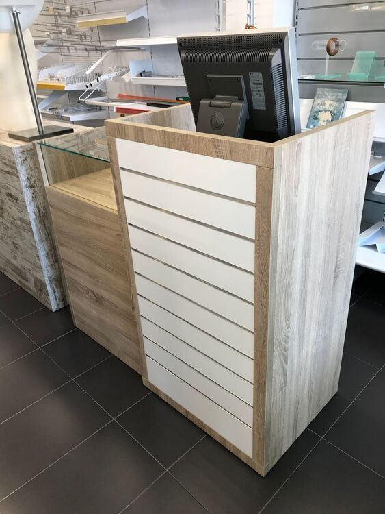 Un monitor de computadora está colocado encima de un mostrador de madera en una tienda.