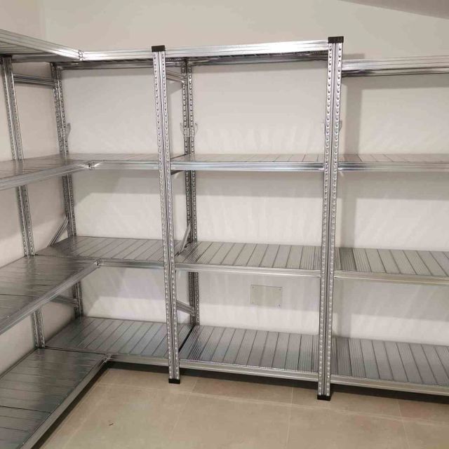 Una habitación con muchos estantes y una pared blanca.