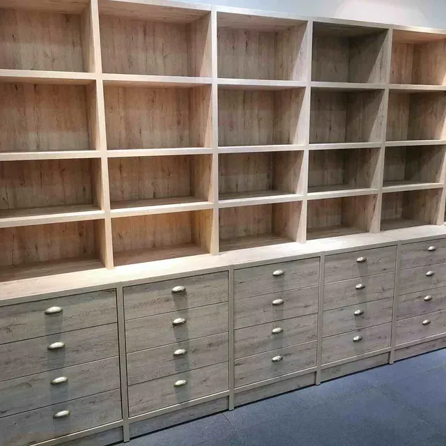 Una fila de estantes y cajones de madera en una habitación.
