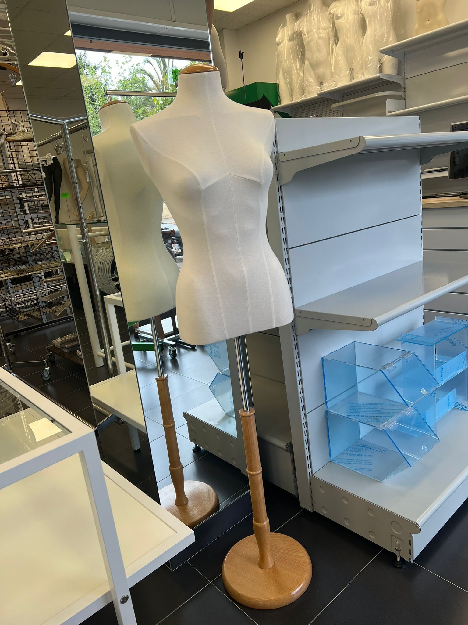 Un maniquí femenino está sentado en una tienda rodeado de estantes.