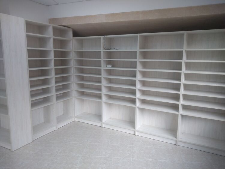 Una habitación con muchos estantes y un rincón.