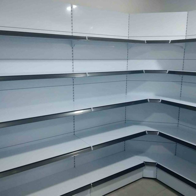 Un rincón de una habitación con muchos estantes vacíos.