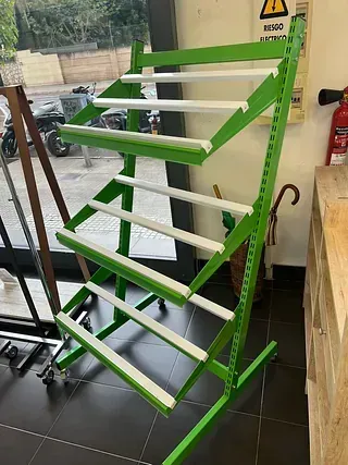 Un estante verde y blanco se encuentra sobre un piso de baldosas en una habitación.
