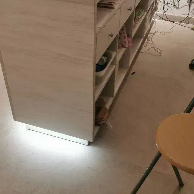 Un taburete de madera se encuentra junto a un armario blanco.