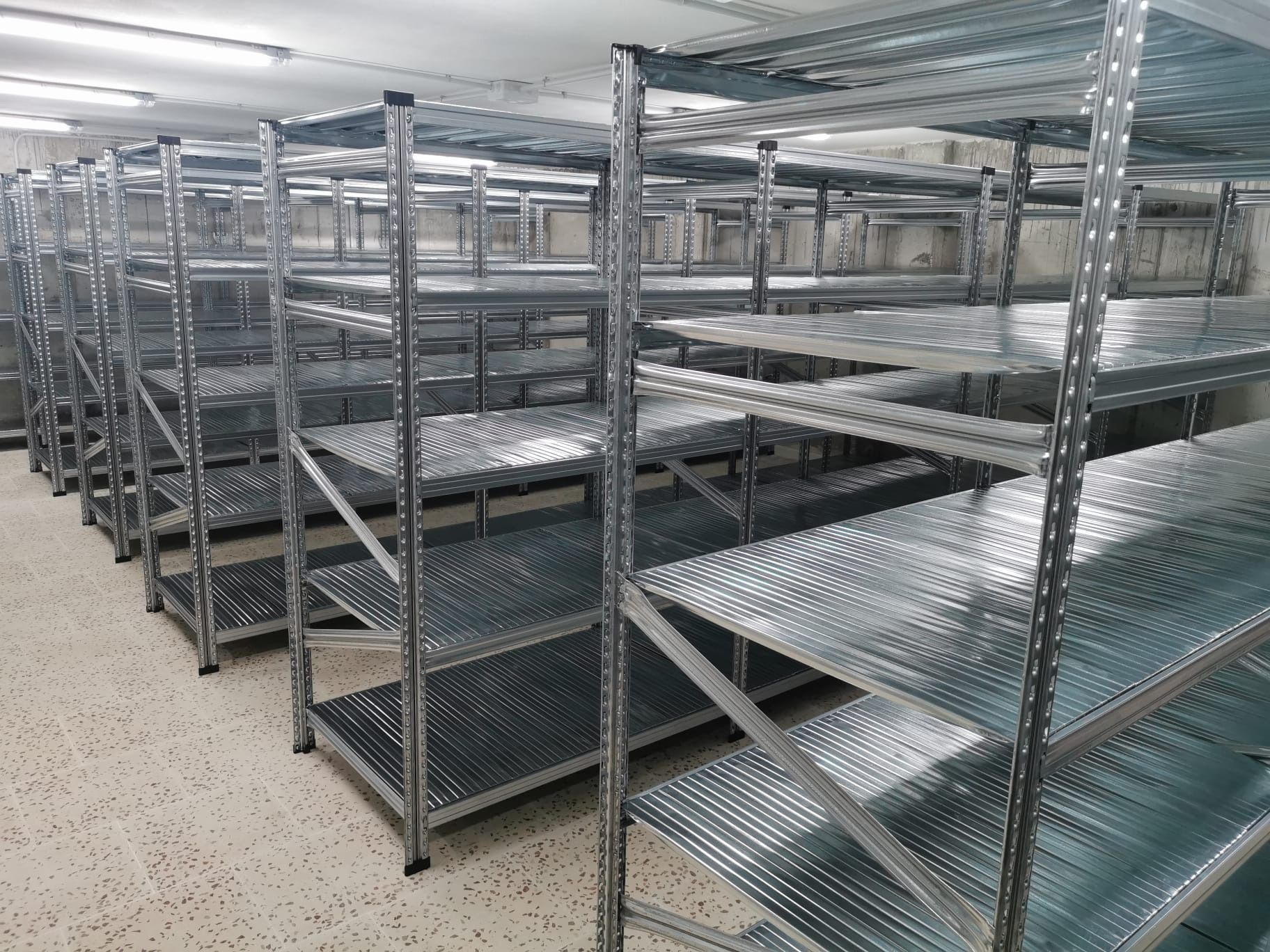 Una fila de estantes de metal están alineados en una habitación.