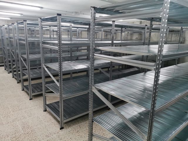 Una fila de estantes de metal están alineados en una habitación.