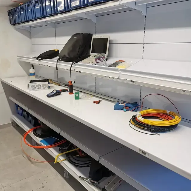 Un estante con una computadora portátil encima y un montón de cables encima.