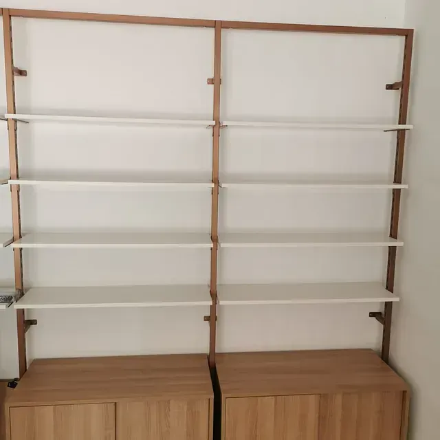 Dos estantes de madera con estantes blancos en una habitación.