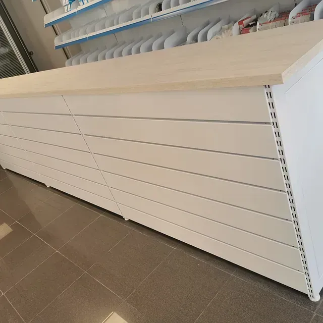 Un largo mostrador blanco con tapa de madera en una tienda.