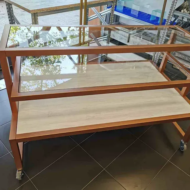 Una mesa de madera con tres estantes y tapa de cristal.