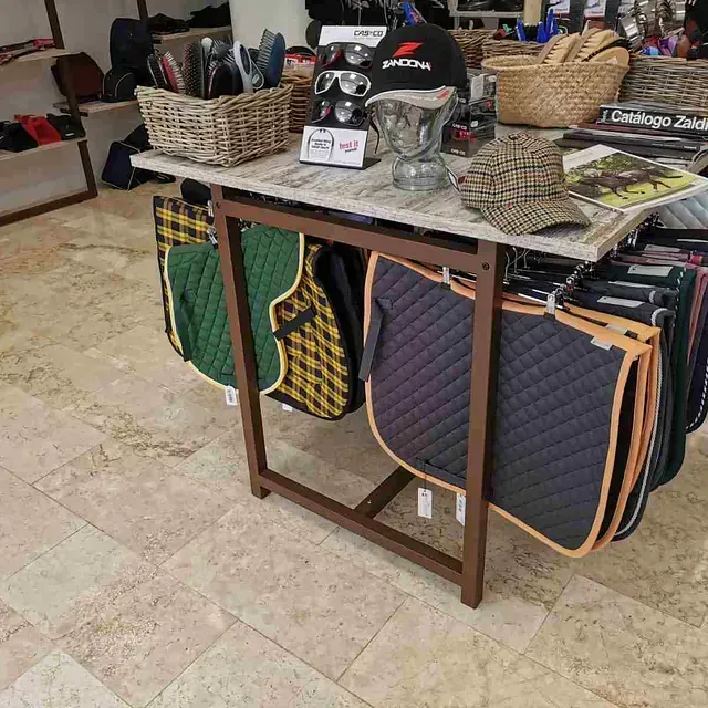 Una mesa con mantas de silla de montar y sombreros sobre ella