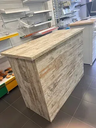 Un mostrador de madera está colocado sobre un suelo de baldosas en una tienda.