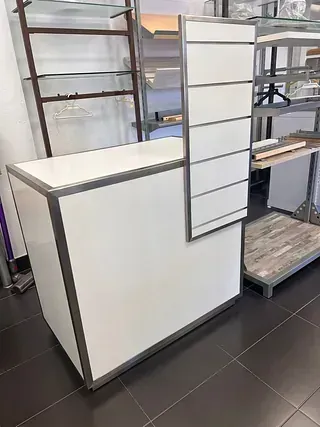 Un mostrador blanco está sobre un piso de baldosas en una tienda.