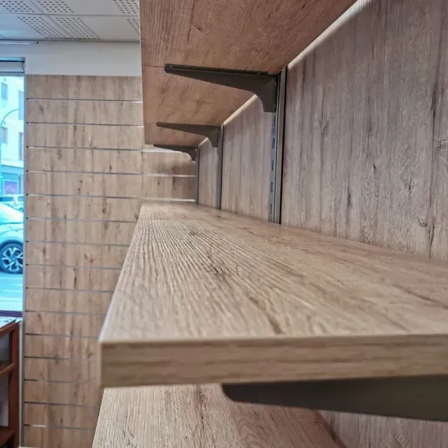 Una fila de estantes de madera contra una pared de madera en una habitación.