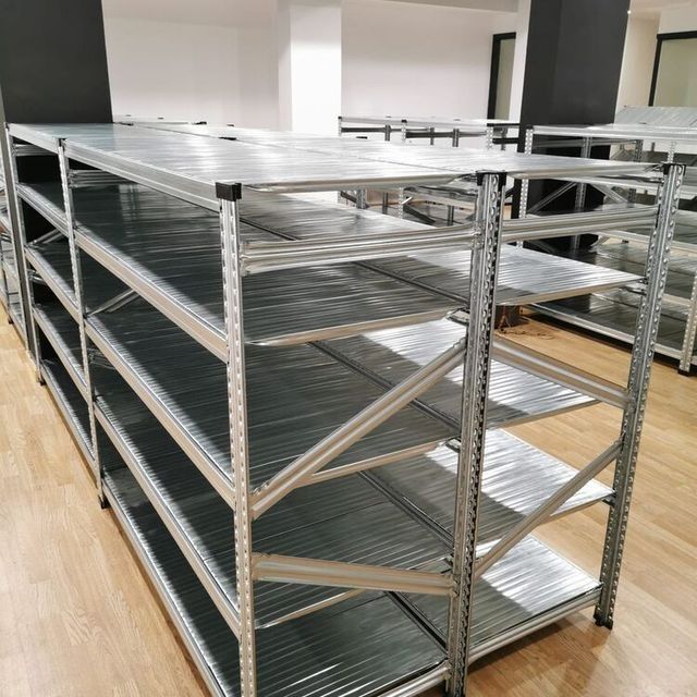 Una fila de estantes de metal en una habitación con pisos de madera.