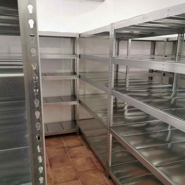 Una habitación con muchos estantes y suelo de baldosas.