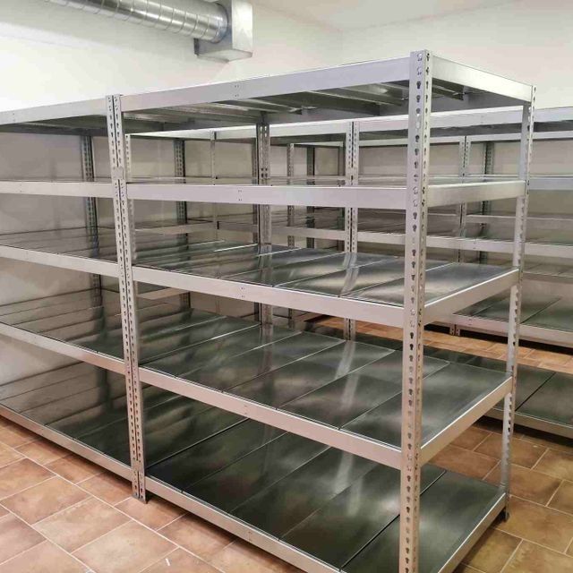 Una fila de estantes de metal están alineados en una habitación.