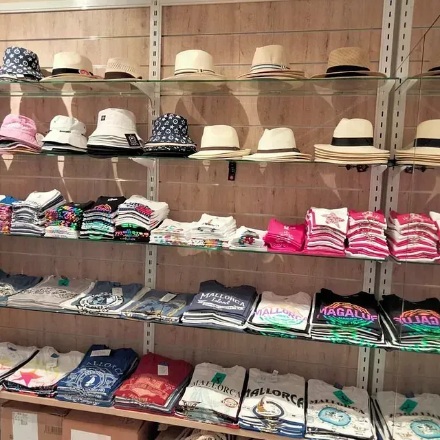 Una exposición de sombreros y camisetas, incluida una que dice Mallorca.