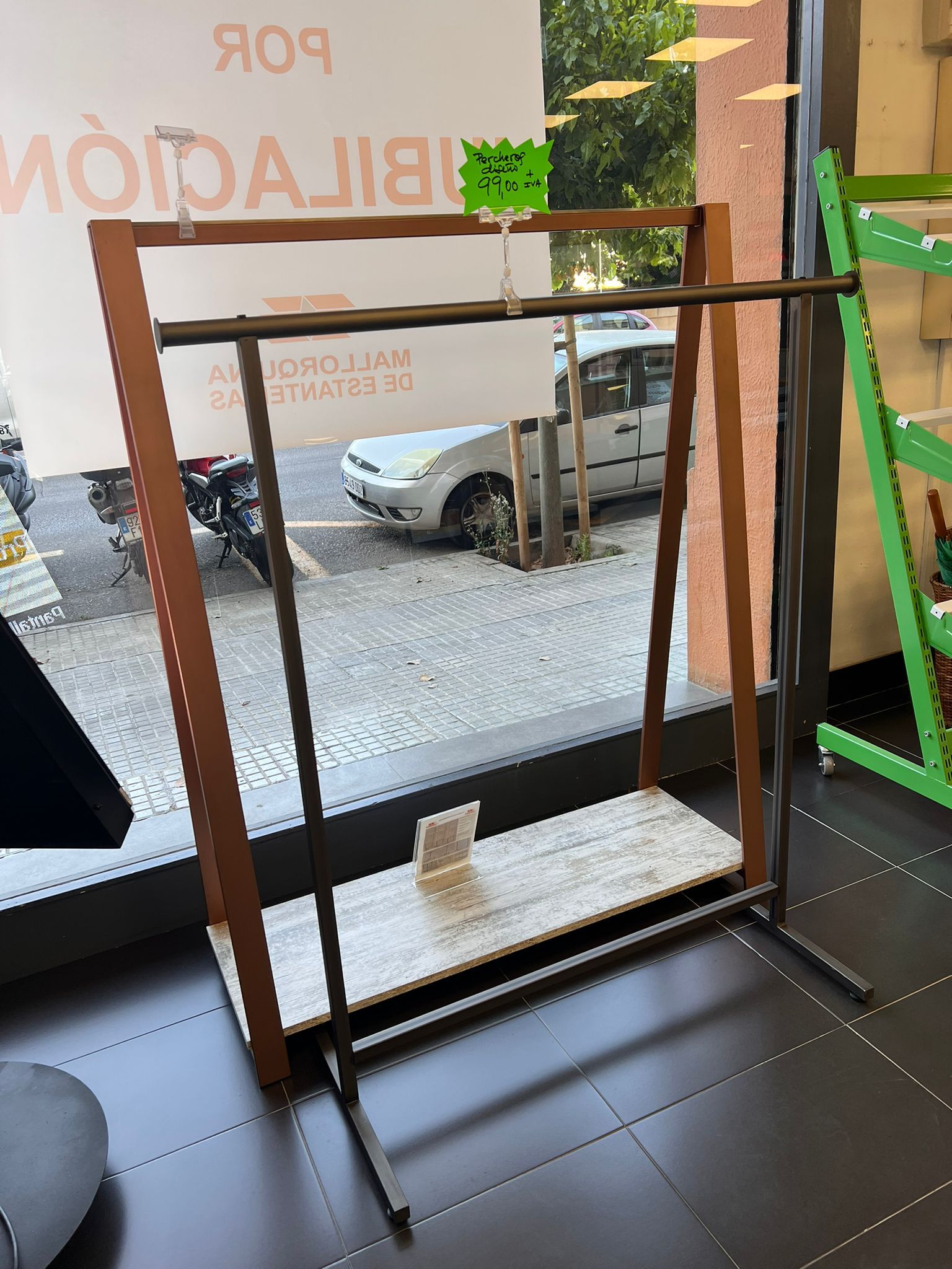Un perchero de acero inoxidable está en una habitación al lado de una ventana.