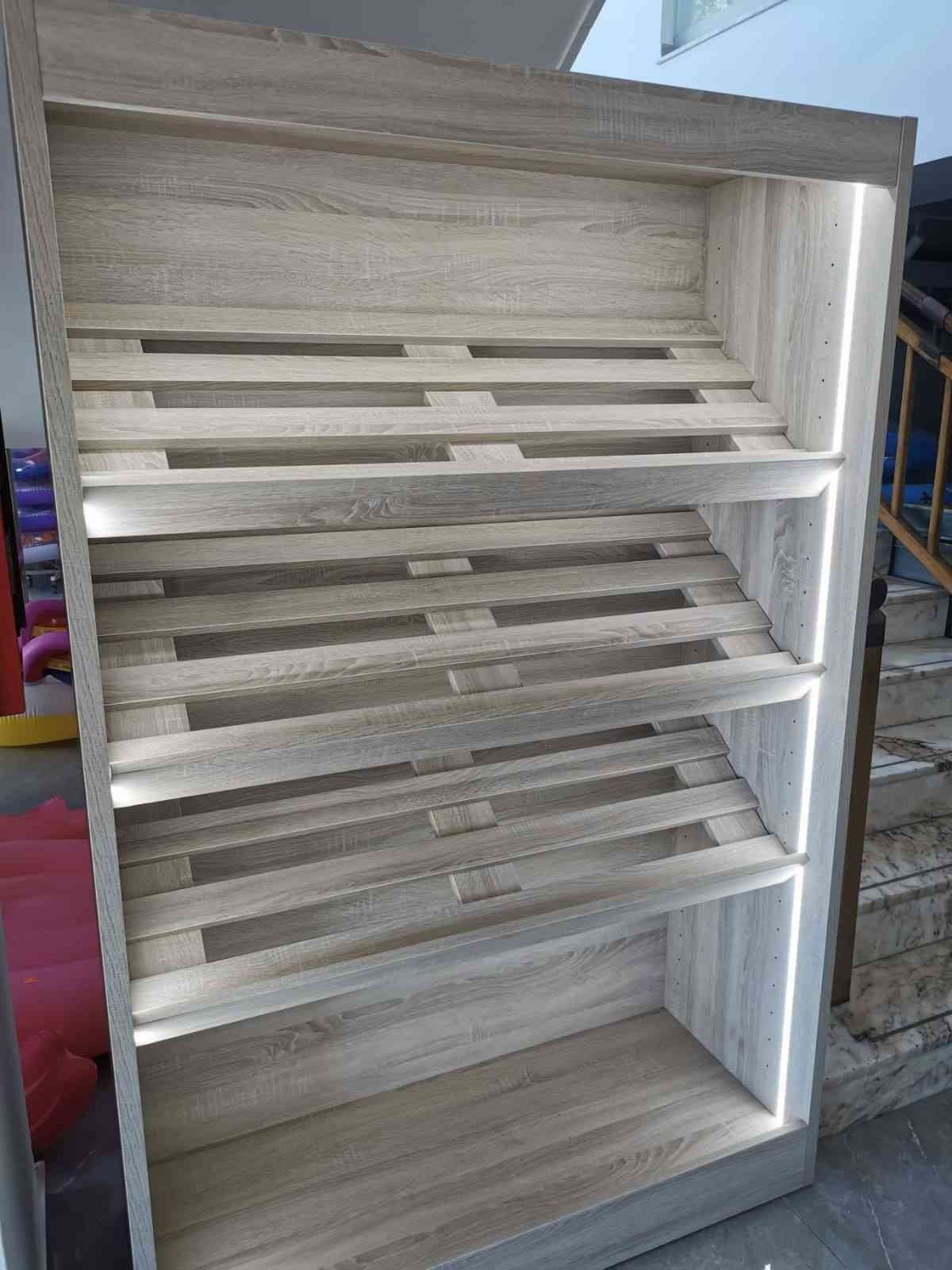 Un estante de madera con luces en los estantes está junto a una escalera.