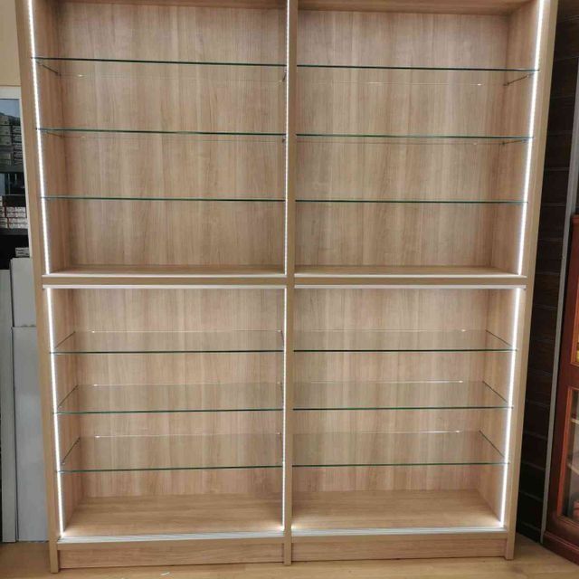 Una estantería de madera con estantes de cristal y una luz detrás de ella.