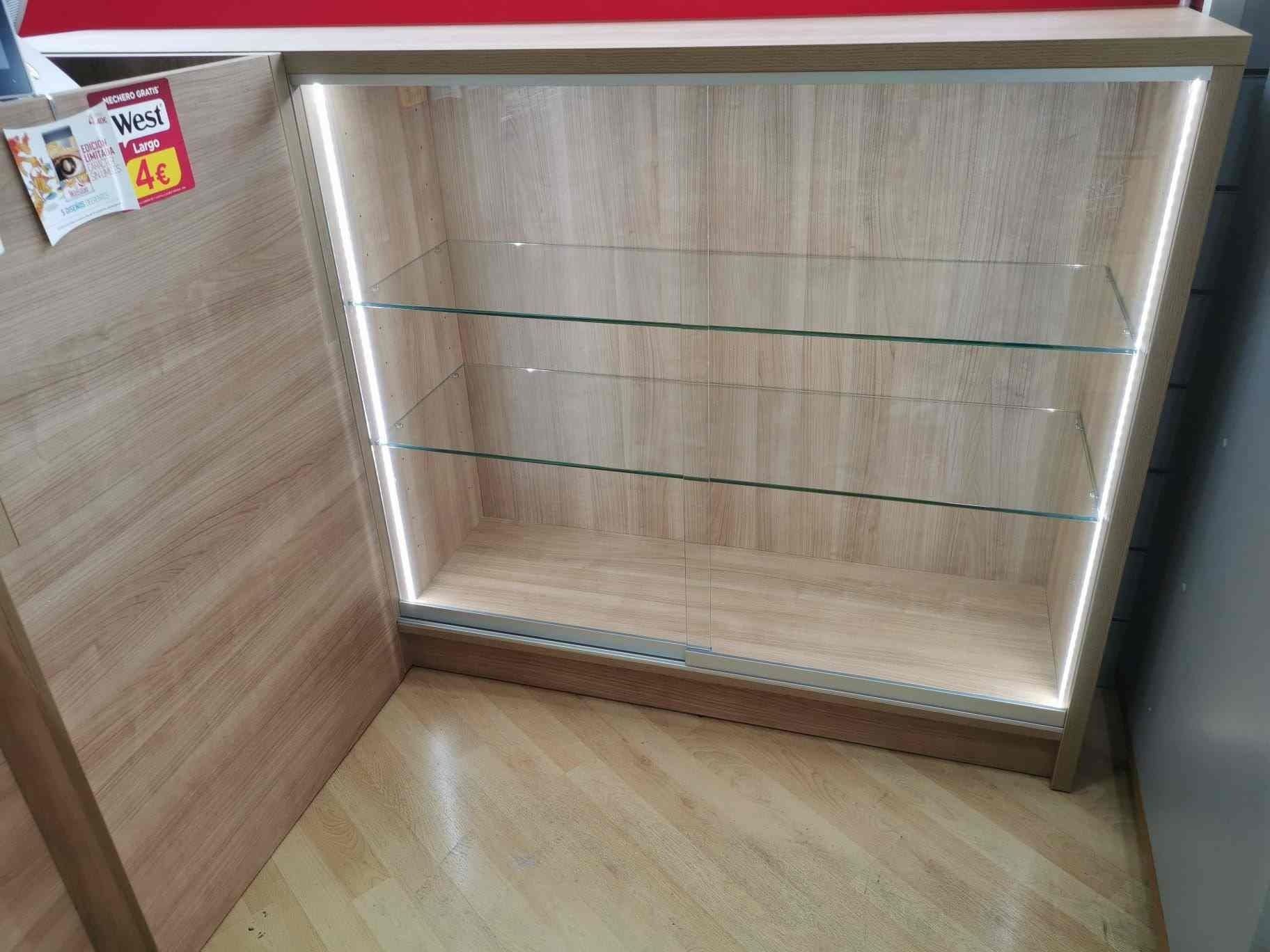Un armario de madera con estantes de cristal y una luz detrás.