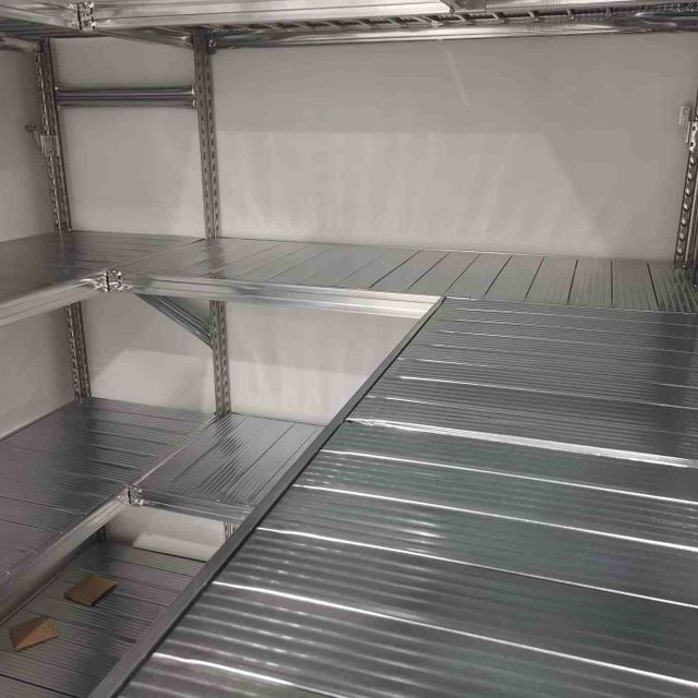 Una habitación con muchos estantes y suelo de metal.