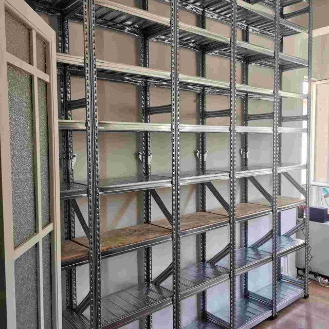 Una fila de estantes de metal con estantes de madera en una habitación.