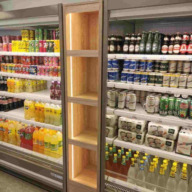 Un pasillo de una tienda de comestibles lleno de latas y botellas de refresco.