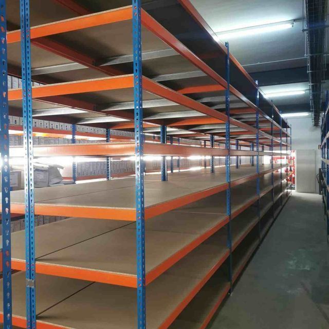 Un almacén vacío con estantes naranjas y estantes azules.
