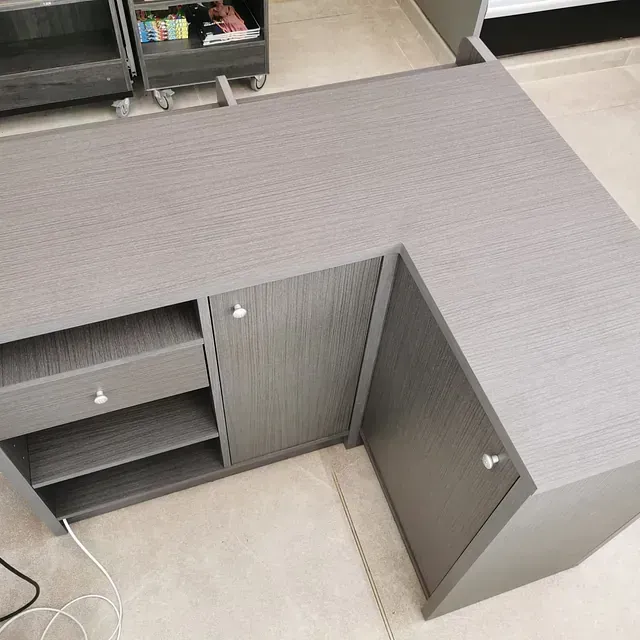 Un escritorio gris en forma de L con cajones y estantes.