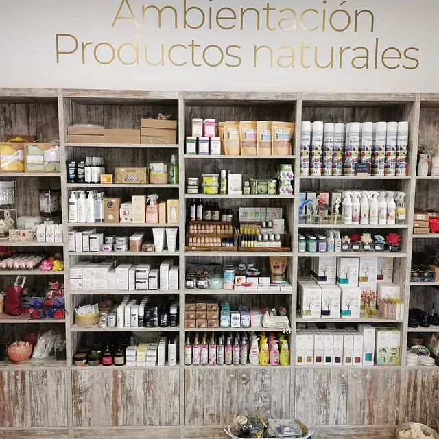 Una pared de estanterías llenas de muchos productos y un cartel que dice ambientación productos naturales