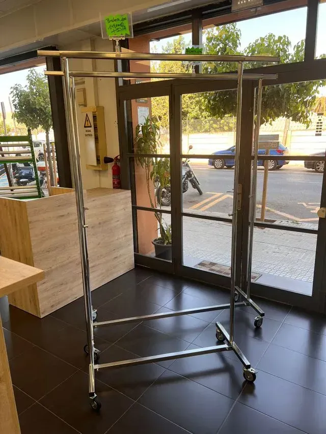 Un perchero está en una habitación al lado de una ventana.