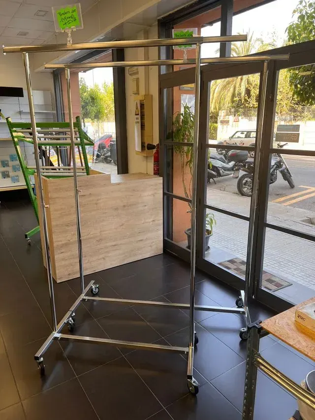 Un perchero está en una habitación al lado de una ventana.