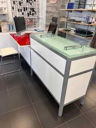 Un mostrador blanco con tapa de cristal en una tienda.