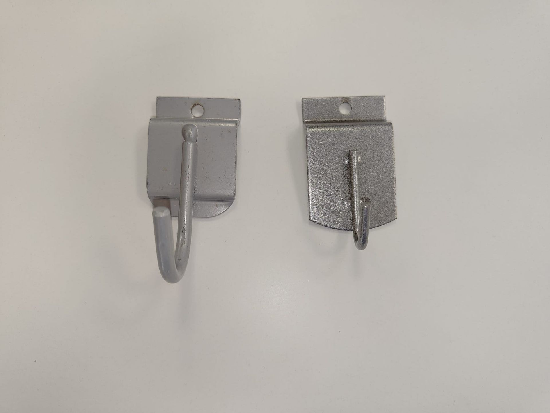 Dos ganchos de metal cuelgan de una pared blanca.